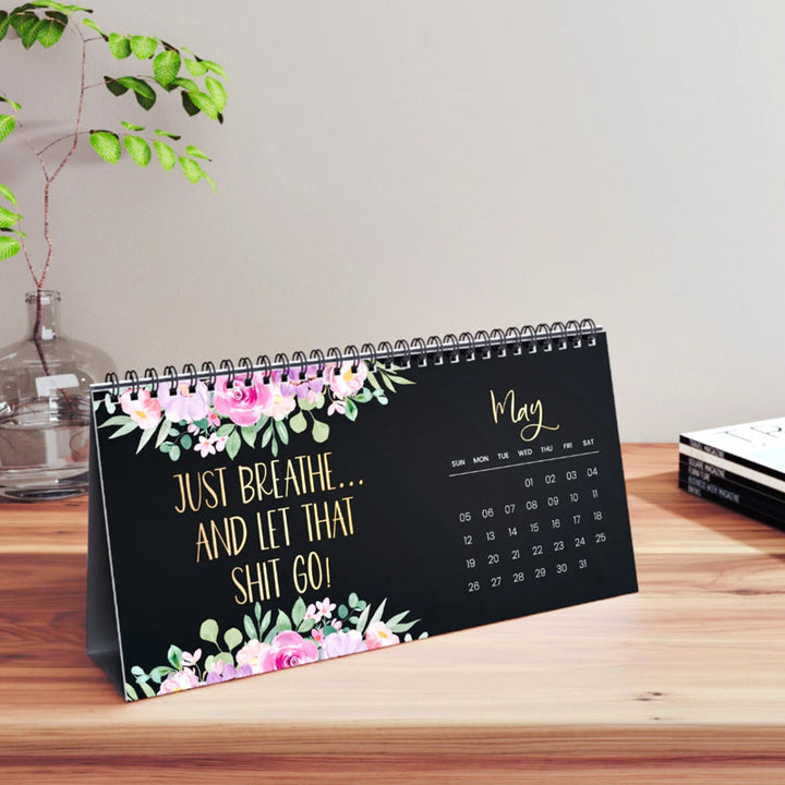 Artistic rendering of a 2025 desk calendar, open to a winter month with a reflective quote