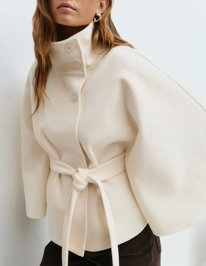 Full-body view of a women's belted high-neck cape coat, an essential piece of spring outerwear.