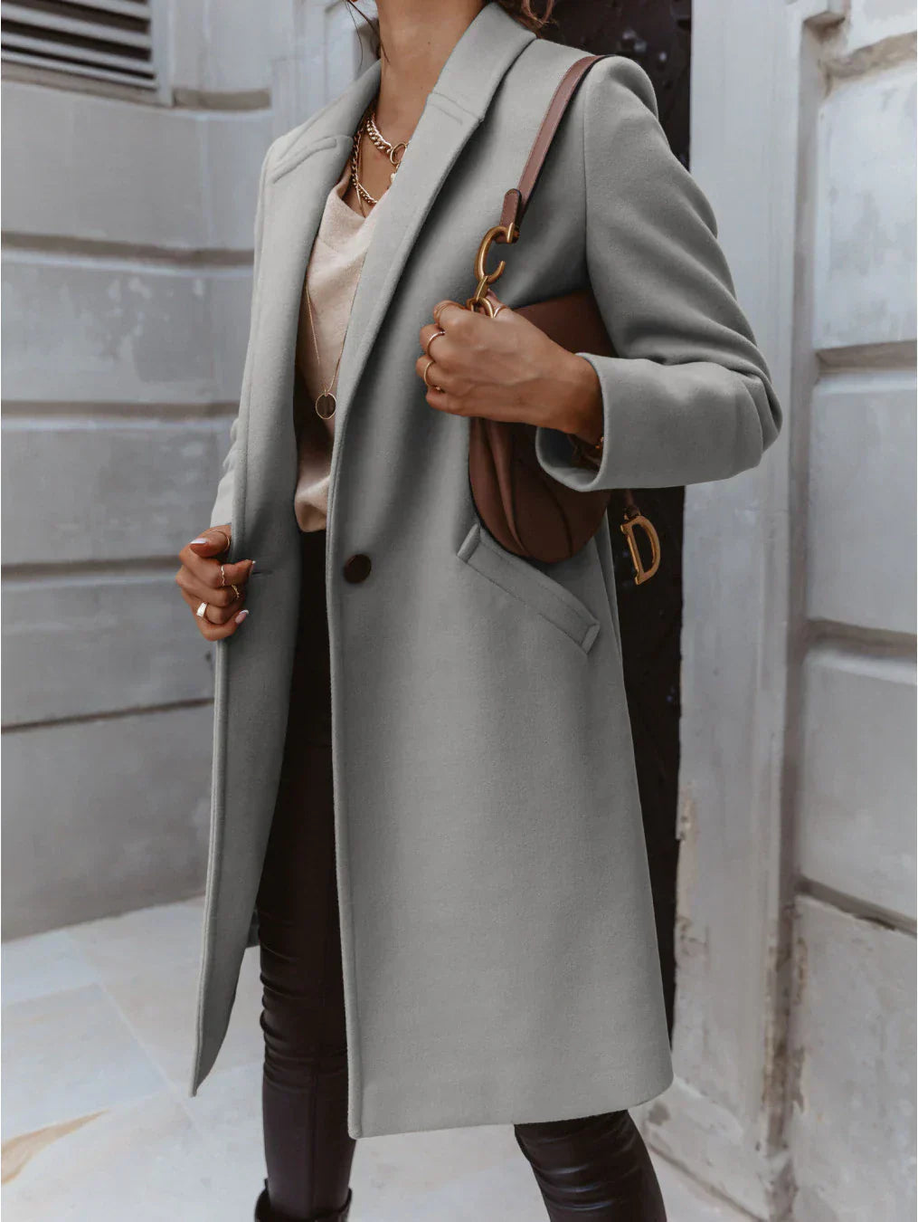 Close-up of the double-breasted button detail on a women's elegant beige trench coat.
