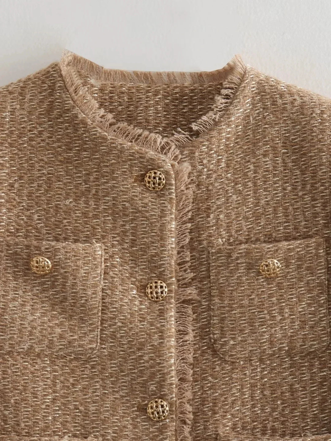 Close-up of a women's tweed button-down jacket, highlighting the fabric texture and button detail.