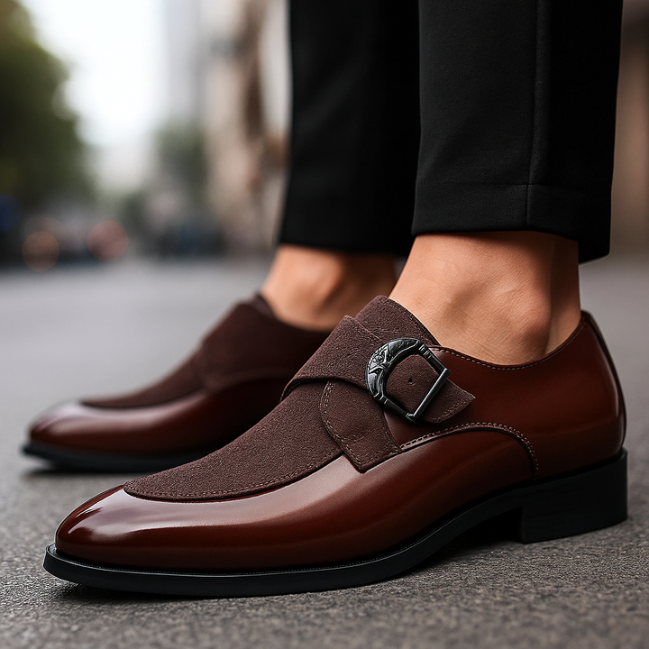 Close-up of a men's black suede loafer with a polished metal buckle, highlighting texture and quality.