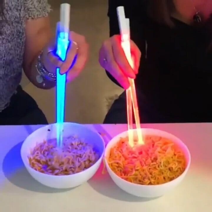 Pair of unisex novelty Lightsaber LED chopsticks glowing red, perfect for fun dining experiences.