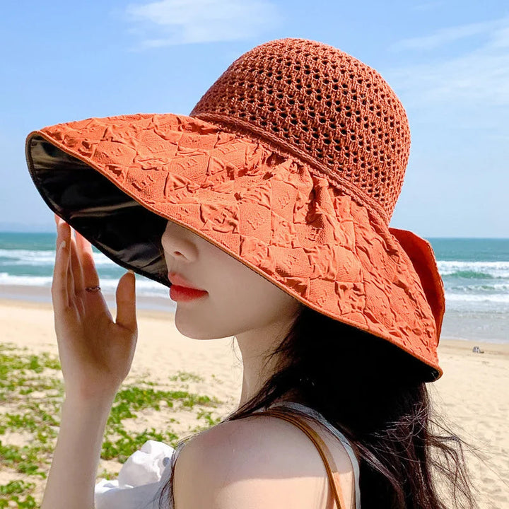 Women's sun hat with a bow, wide brim and foldable design, against a bright outdoor background.