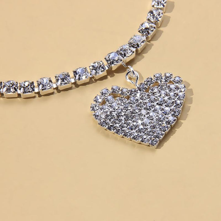 Close-up of a women's silver anklet adorned with a beautiful rhinestone heart charm and foot chain.