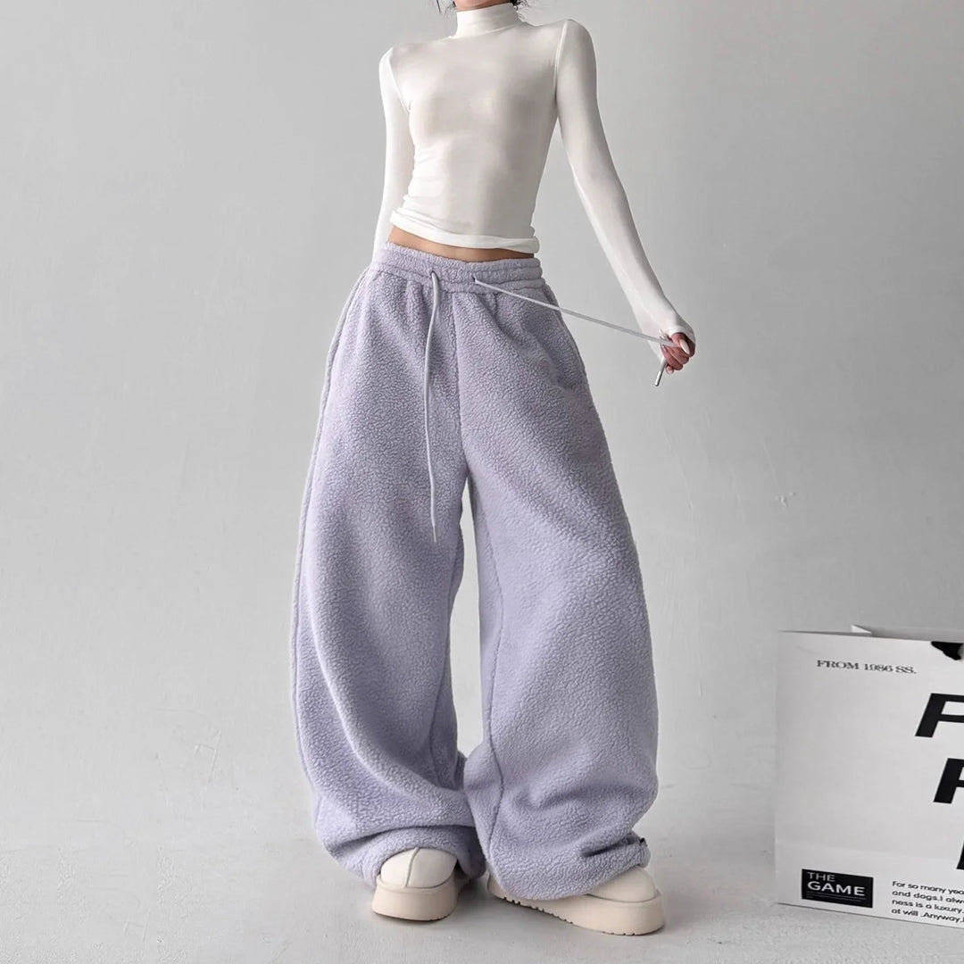 Stack of colorful women's fleece wide-leg lounge pants: navy, gray, and purple, for athleisure