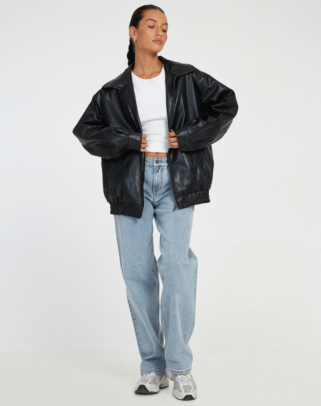 Model wearing a brown oversized faux leather bomber jacket, styled for a casual streetwear look.