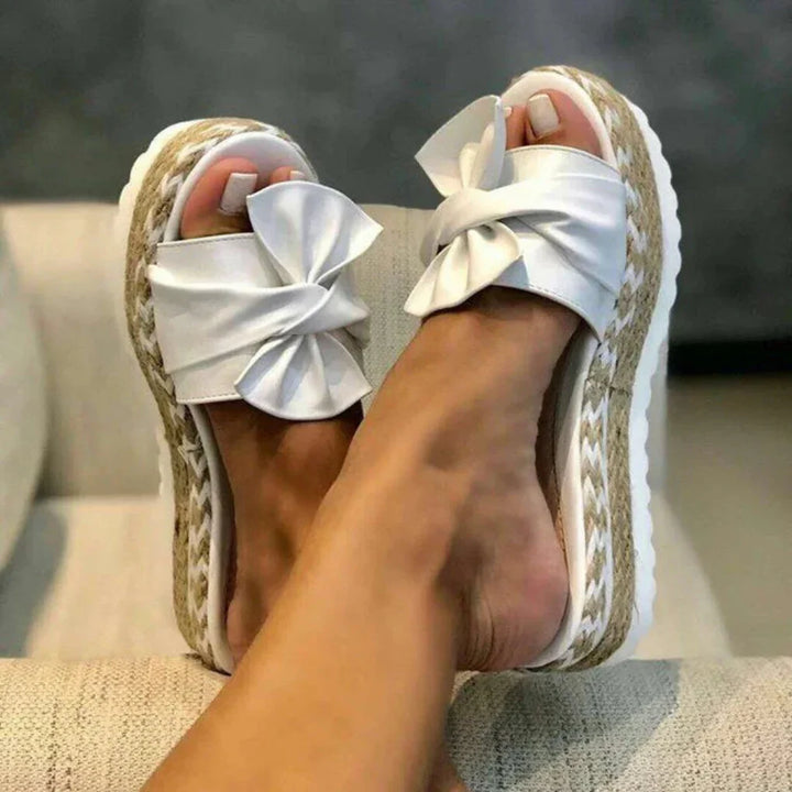 Stylish women's slide sandals featuring a platform sole and decorative bow.